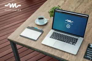 A Macbook on a desk displaying a personalized video from Mediawide