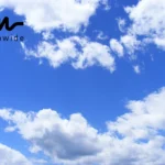 A clear blue sky with soft, fluffy white clouds floating peacefully.