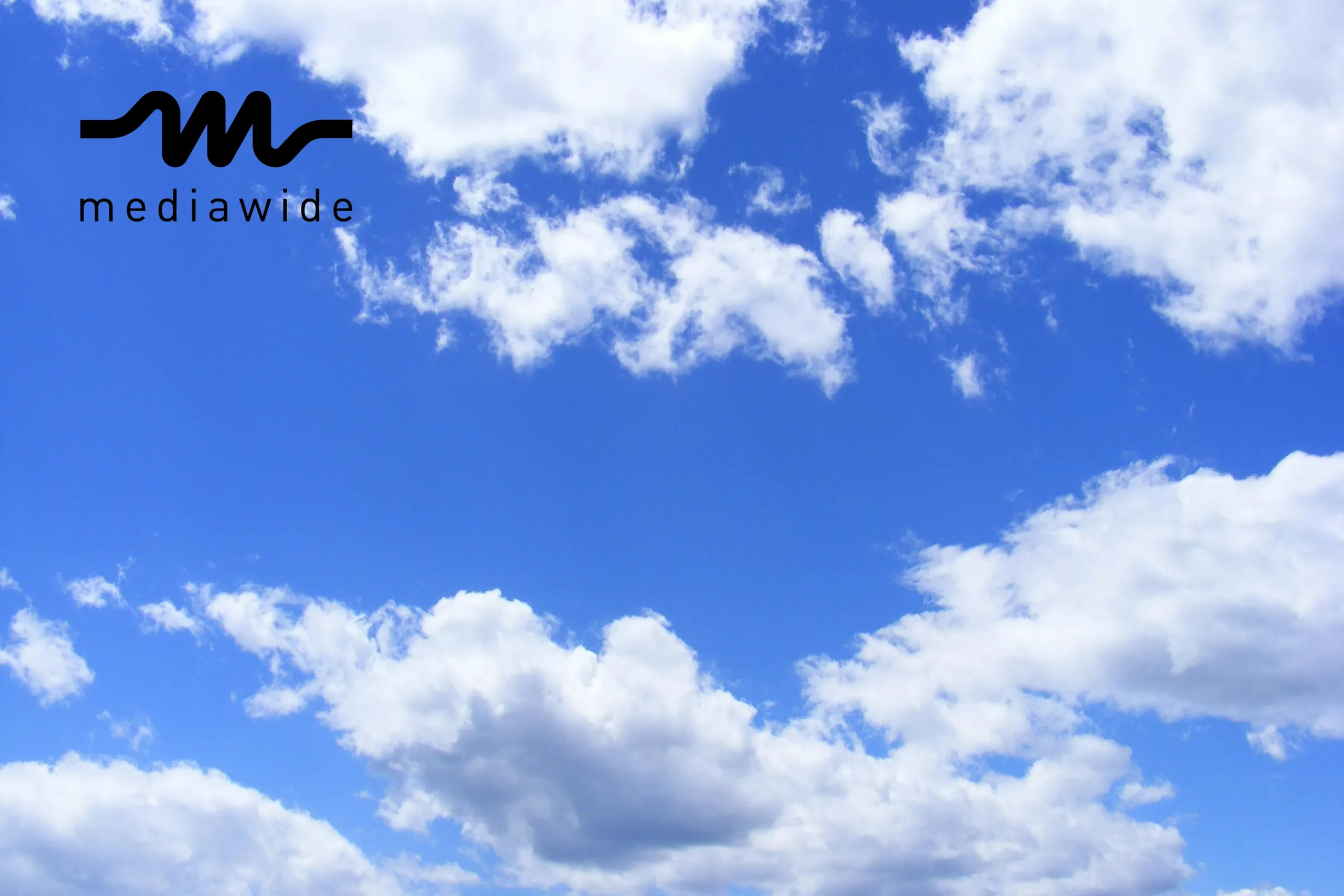 A clear blue sky with soft, fluffy white clouds floating peacefully.